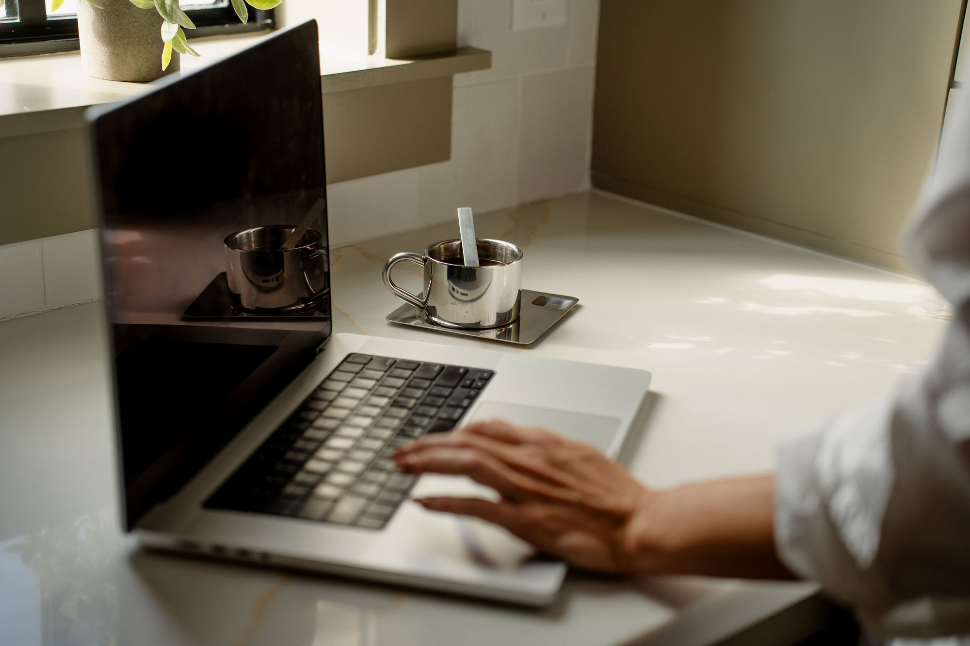 Laptop and coffee on counter, representing a calm workspace for real estate website refresh planning