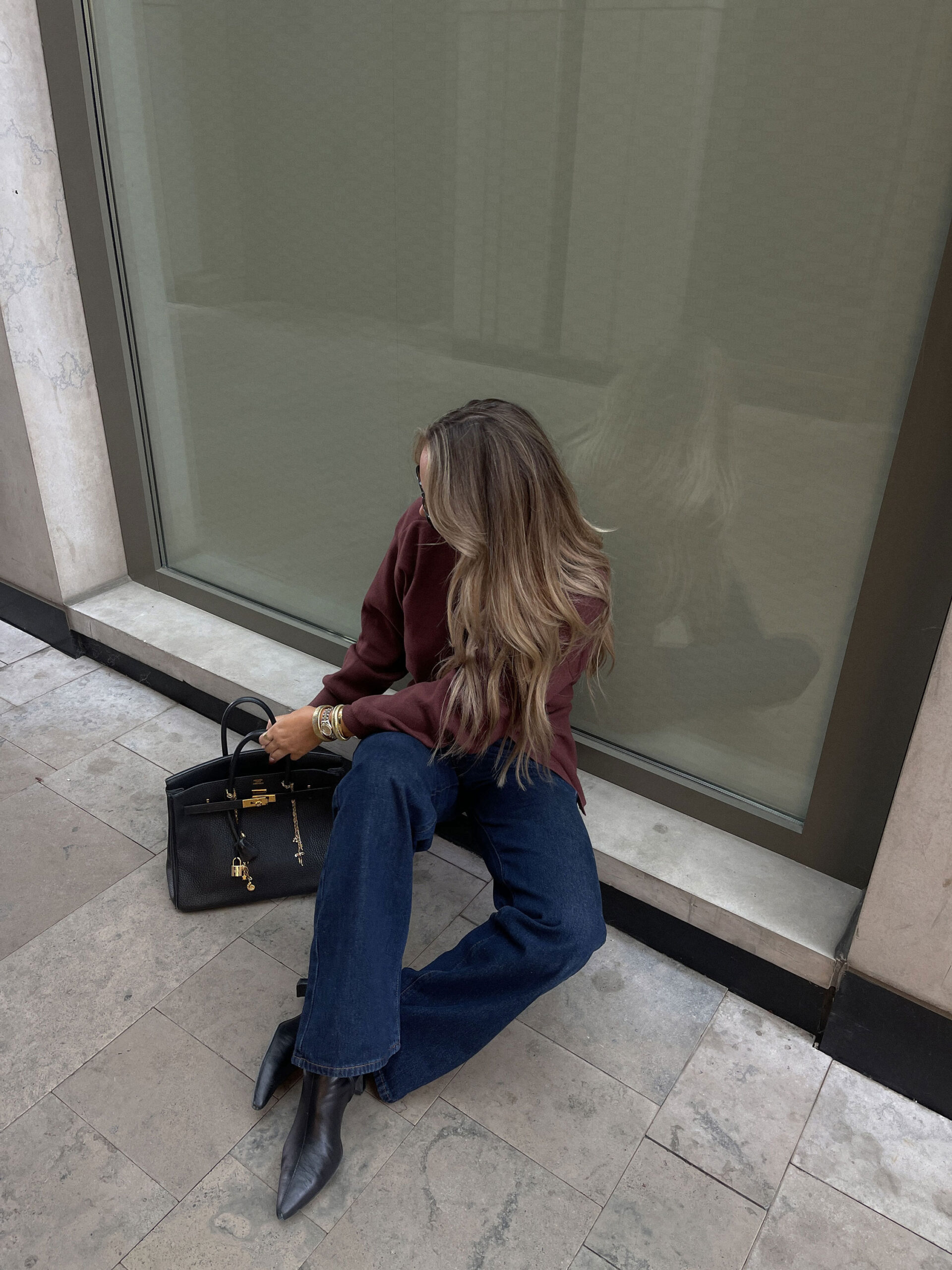 Stylish woman sitting with a luxury handbag, symbolizing modern branding choices for Canadian real estate agents using IDX vs DDF.