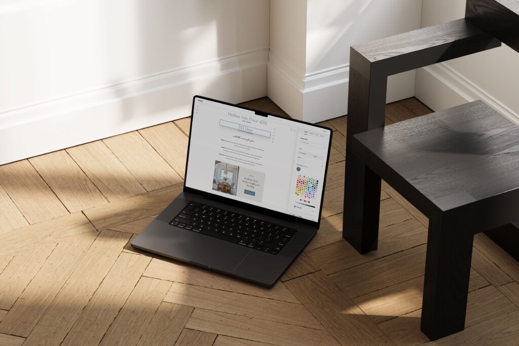 Laptop on a wooden floor with Flodesk open, customizing one of my Lido real estate email templates using the colour and font tools.